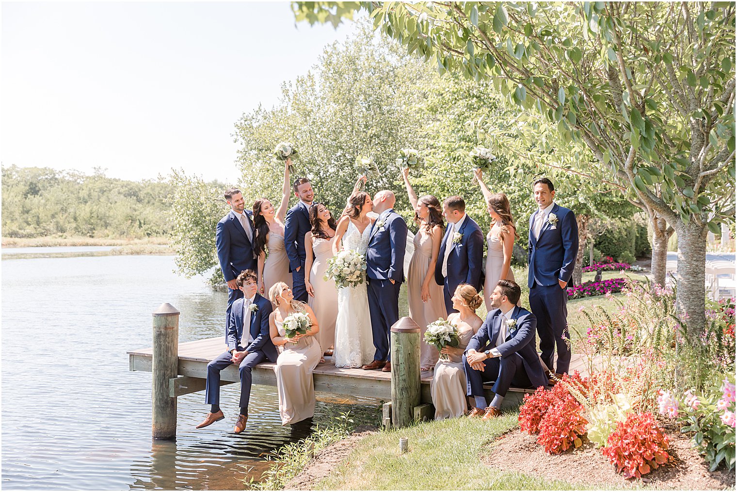 bride and groom cheer with wedding party on dock
