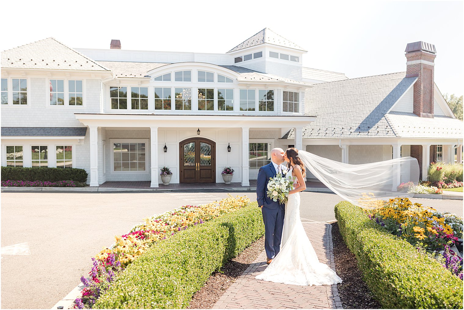 bride and groom pose outside The Mill Lakeside Manor with veil floating behind them