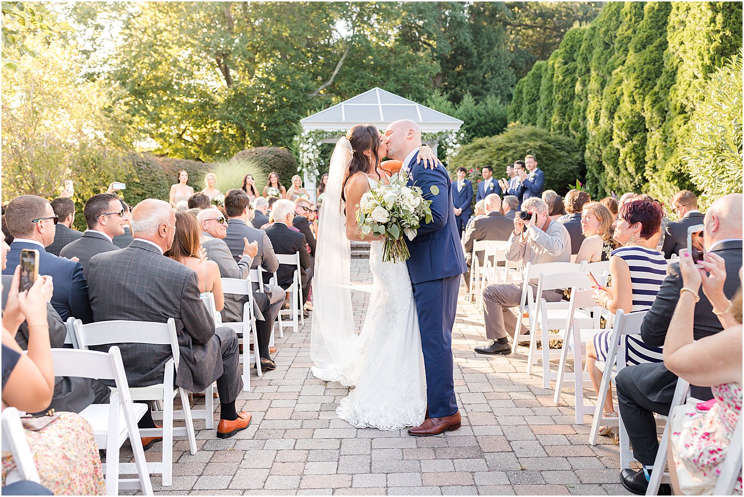 newlyweds kiss in aisle during garden wedding ceremony in New Jersey