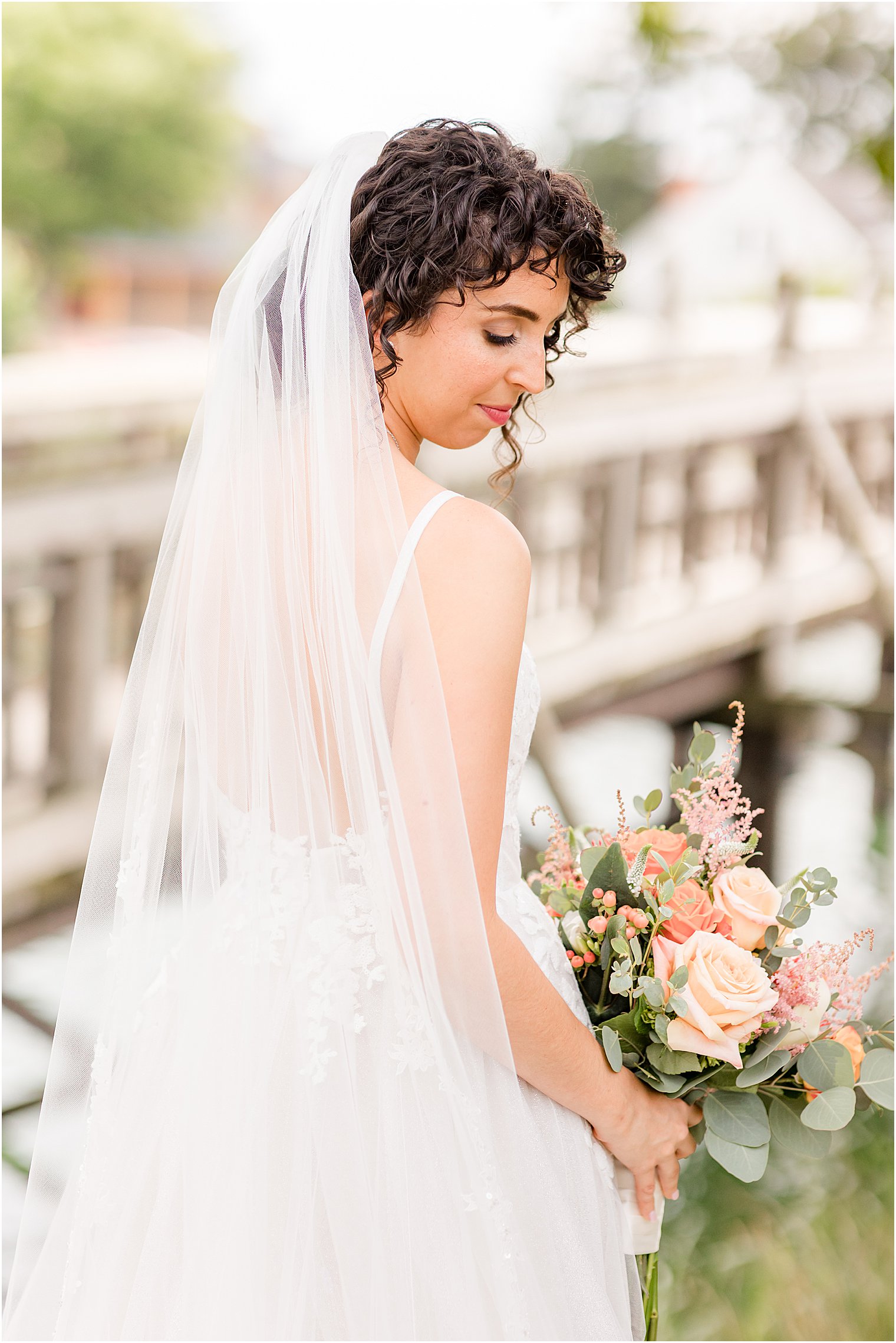 bride looks over shoulders holding bouquet of pastel flowers 