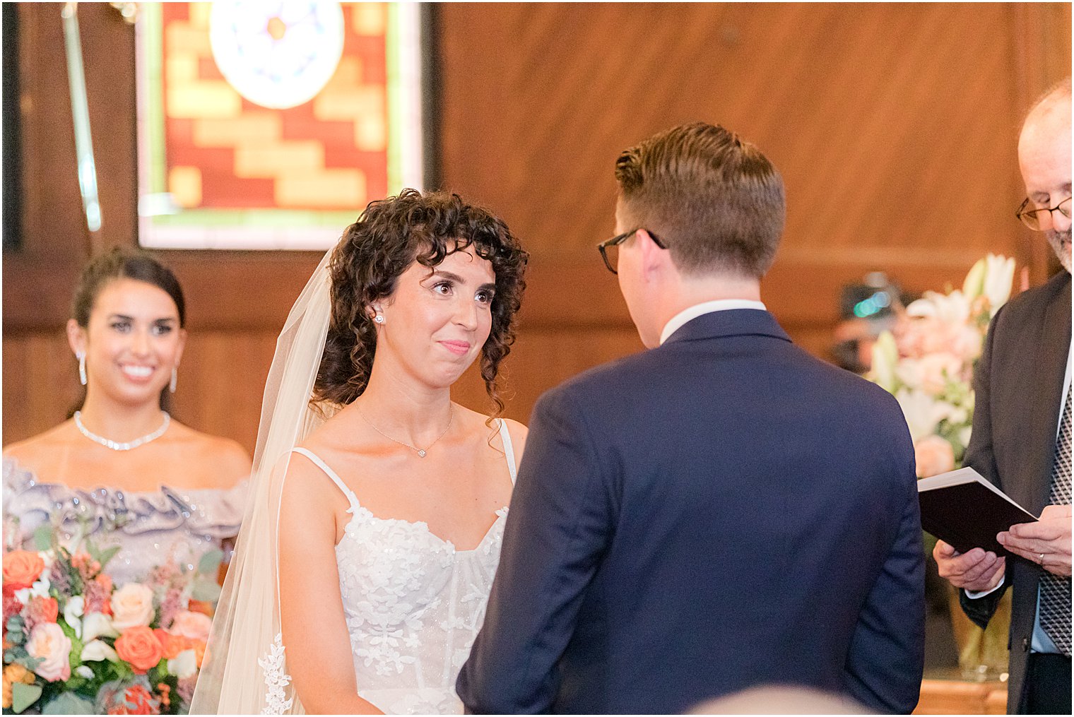 bride smiles at groom during wedding ceremony at St. Andrew's United Methodist Church
