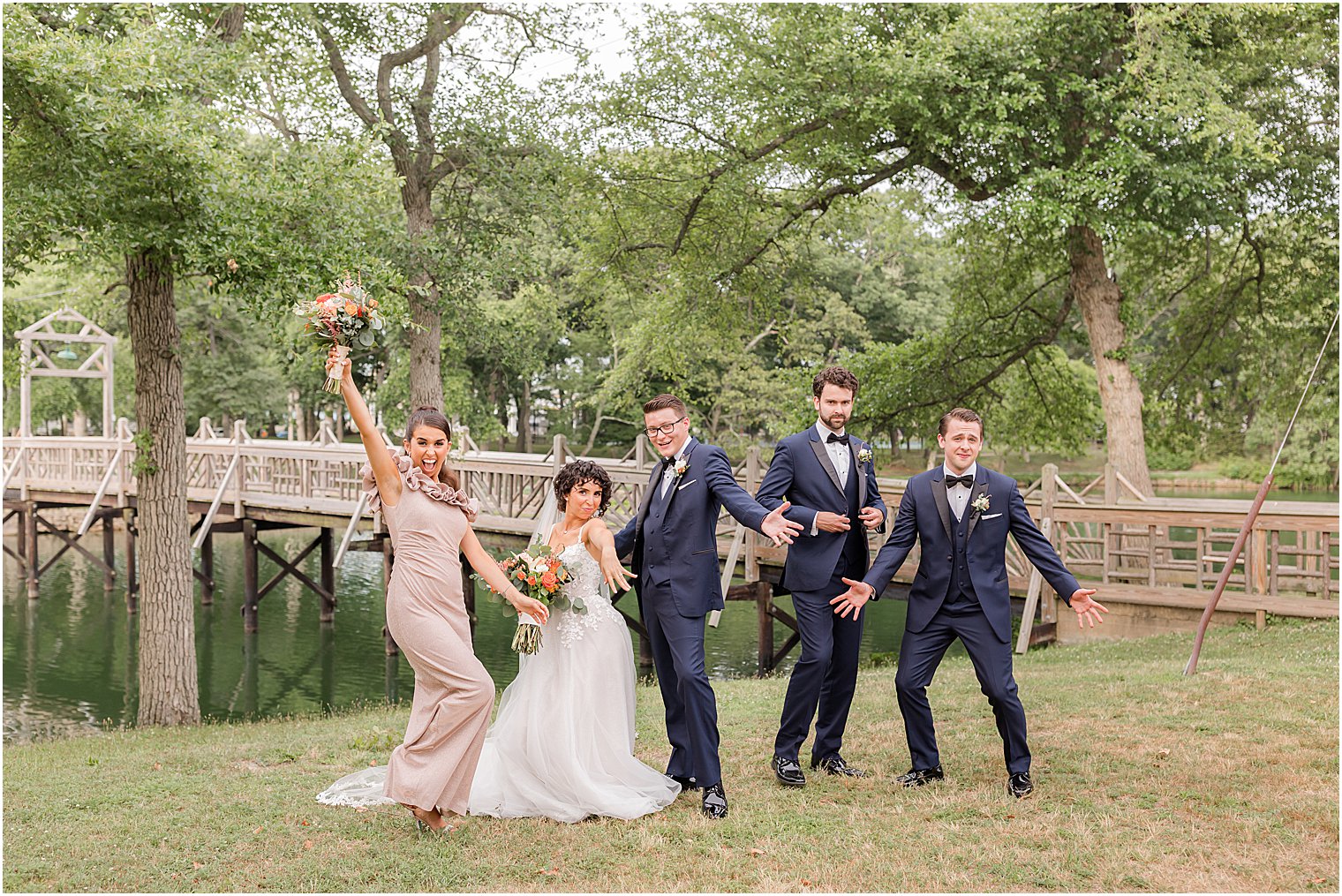 bride, groom, and wedding party jump around during portraits in Spring Lake Park