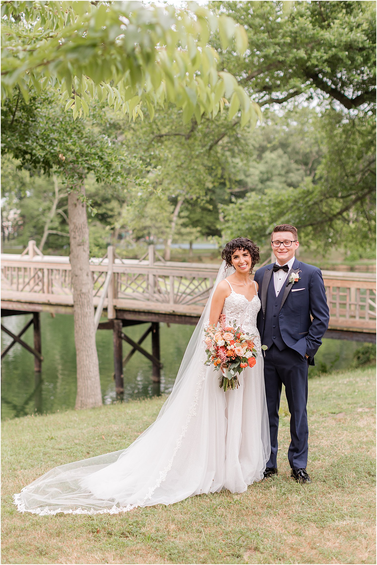 newlyweds stand together by wooden bridge in Spring Lake Park