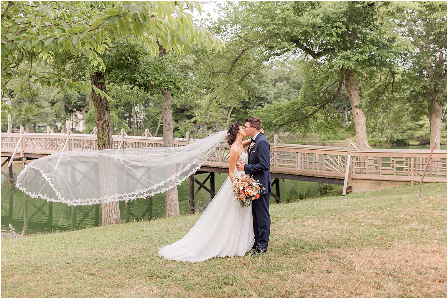 bride and groom hug with bride's veil floating behind them at Spring Lake Park