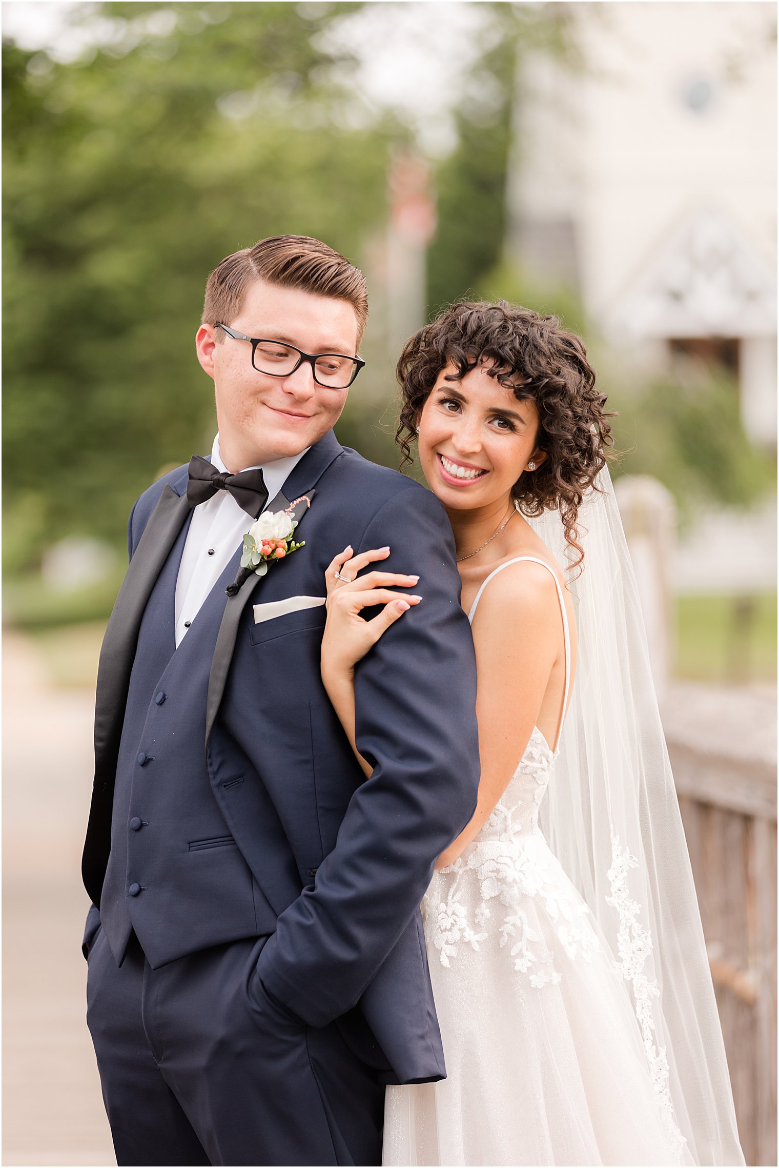 bride hugs groom from behind during portraits on bridge 