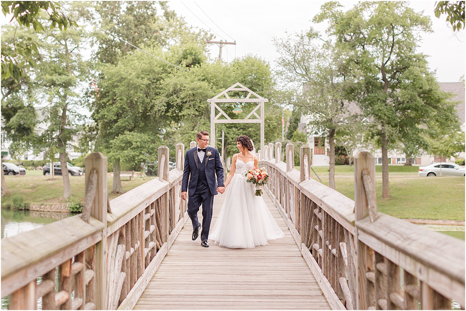 newlyweds walk on wooden bridge in Spring Lake Park