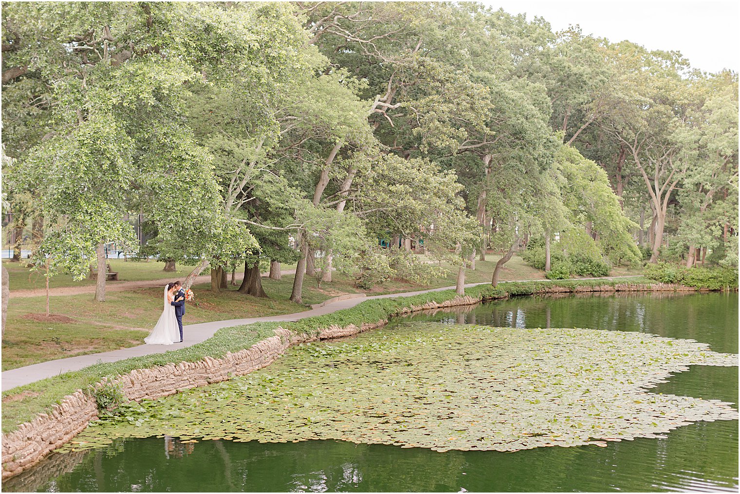 bride and groom walk along pond in Spring Lake, NJ