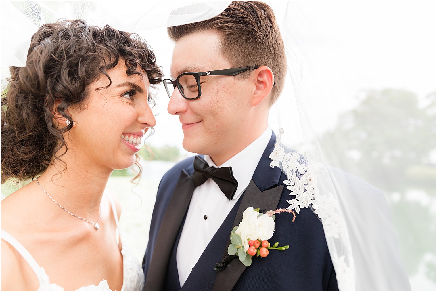bride and groom smile together under bride's veil