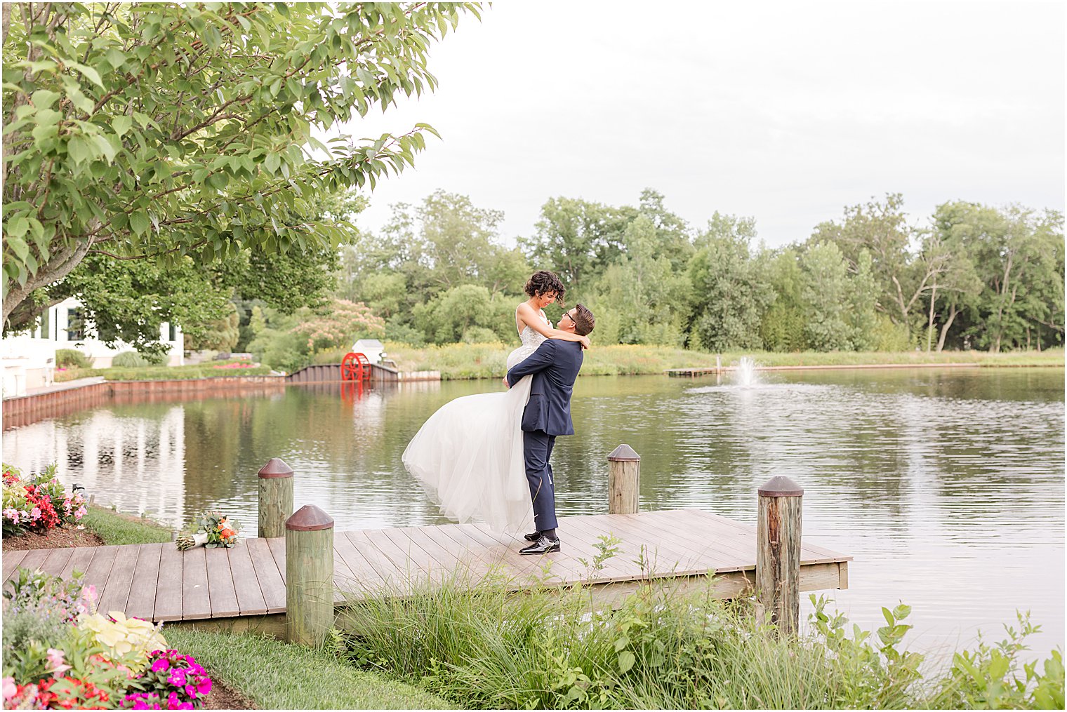 groom lifts bride up on dock at The Mill Lakeside Manor