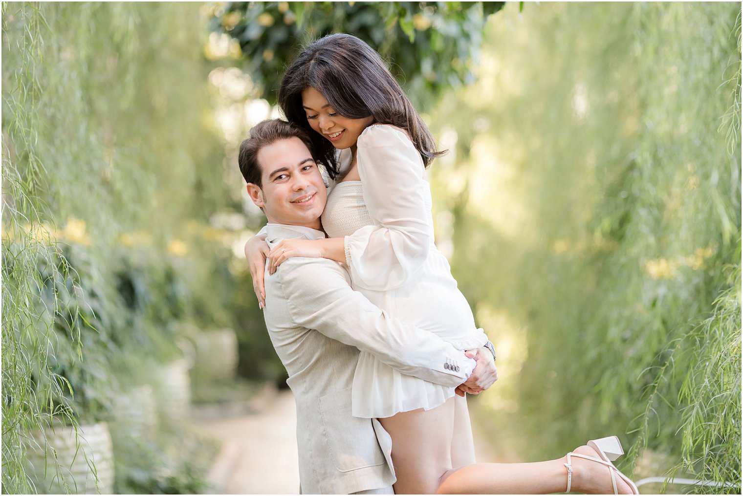 man lifts fiancee up during Longwood Gardens portraits 
