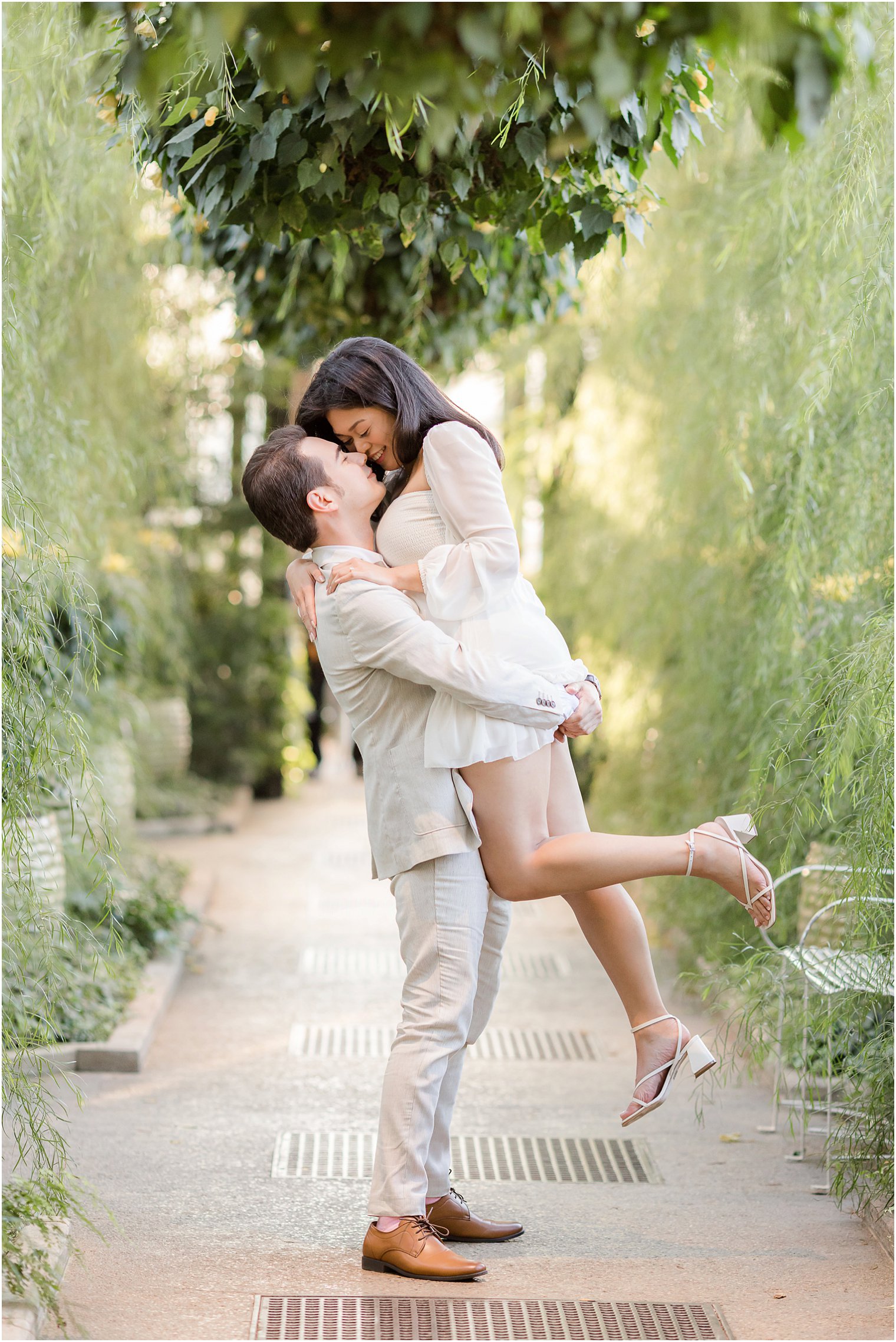 man lifts woman up kissing her during Longwood Gardens proposal