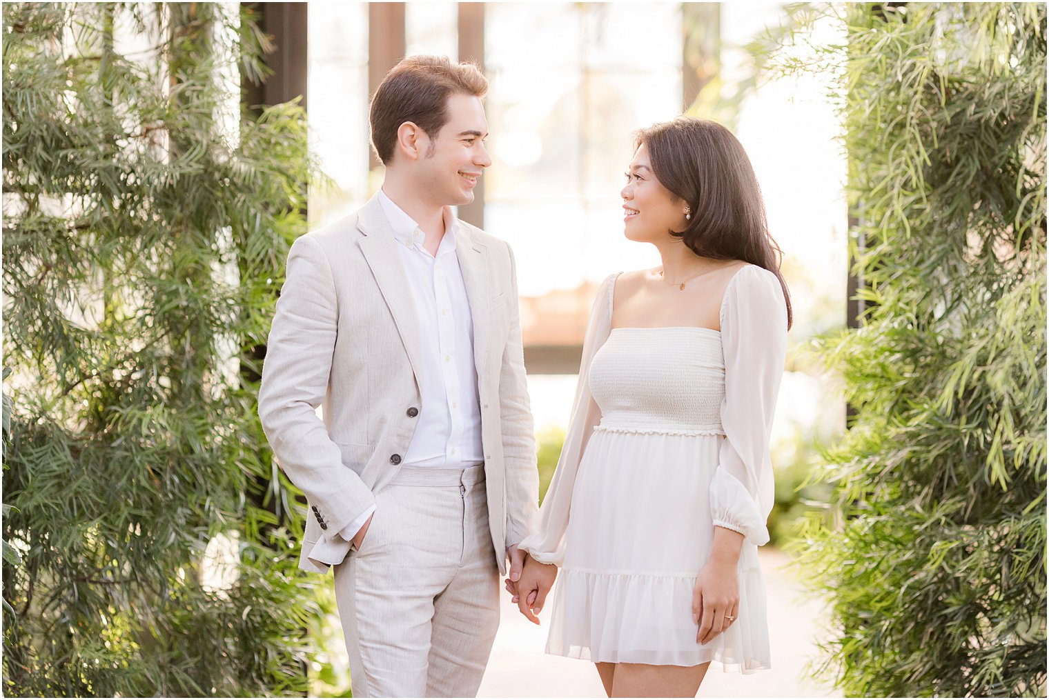 engaged couple holds hands smiling at each other in Longwood Gardens