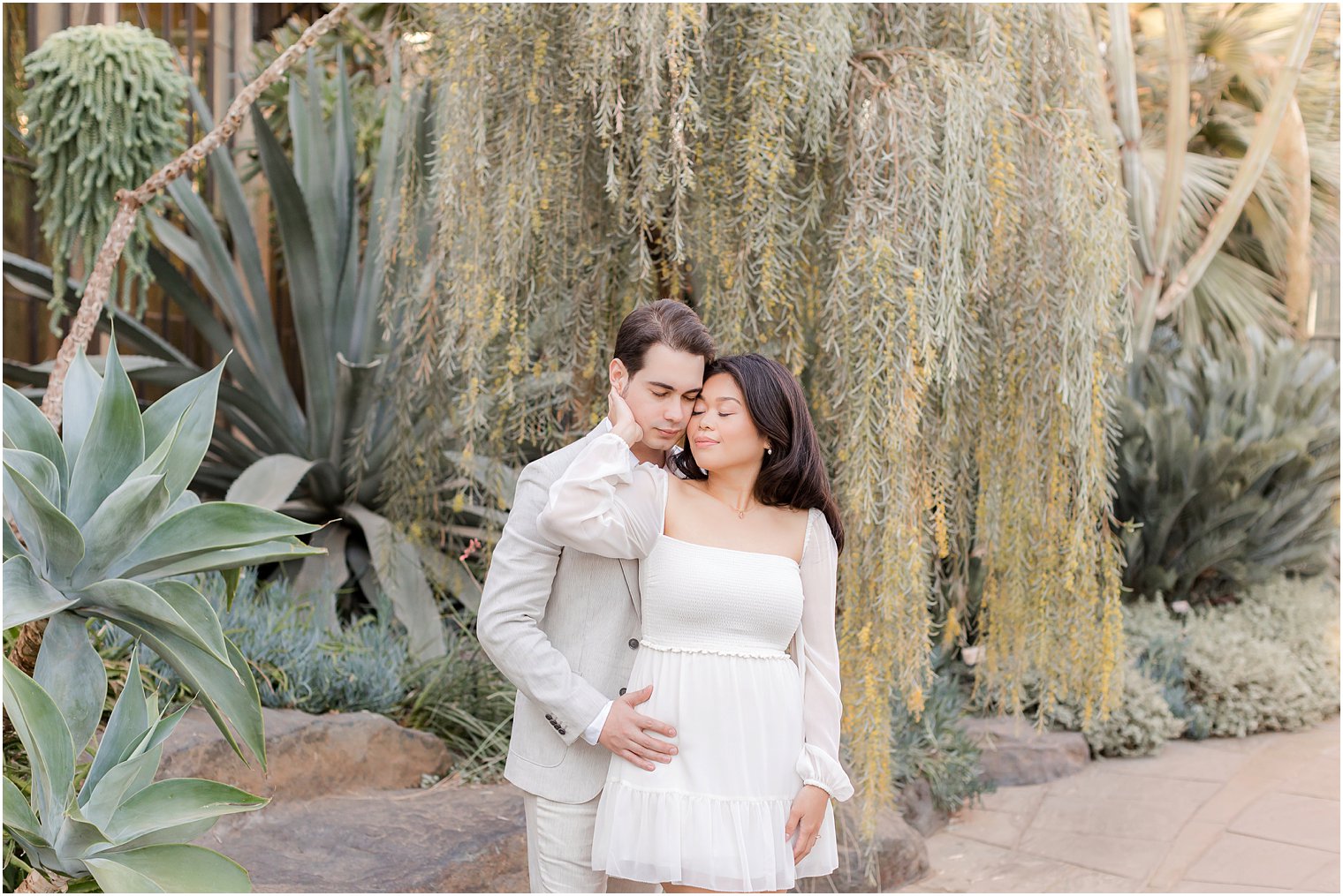 man hugs woman from behind while she holds his head