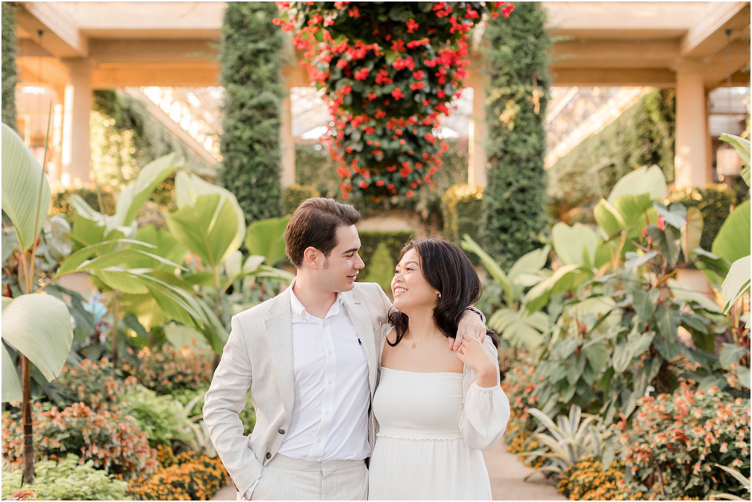 bride and groom smile together by greenery in Longwood Gardens