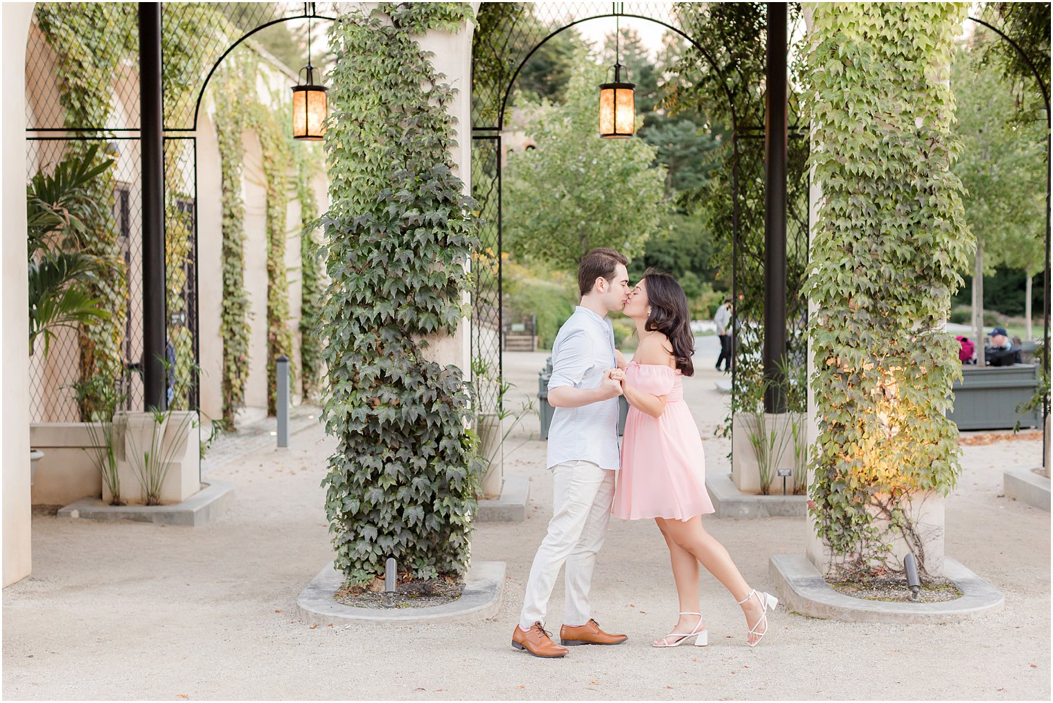 engaged couple kiss by wrought iron gate