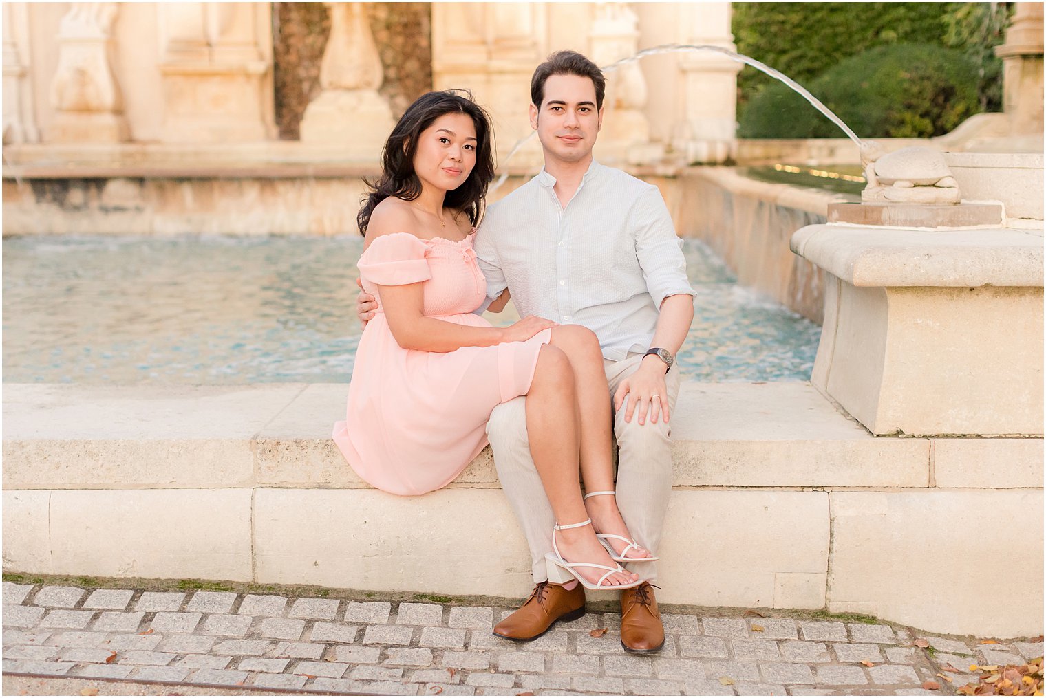 woman sits on fountain with legs over man's lap at Longwood Gardens