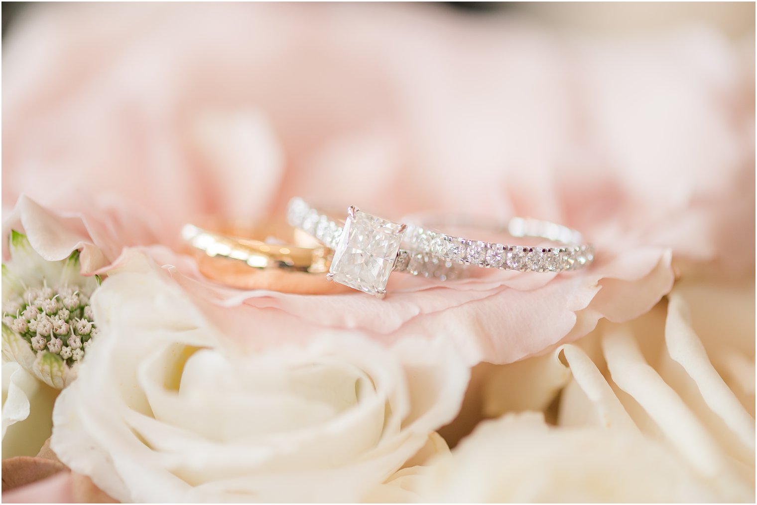 wedding rings rest on pink and ivory roses