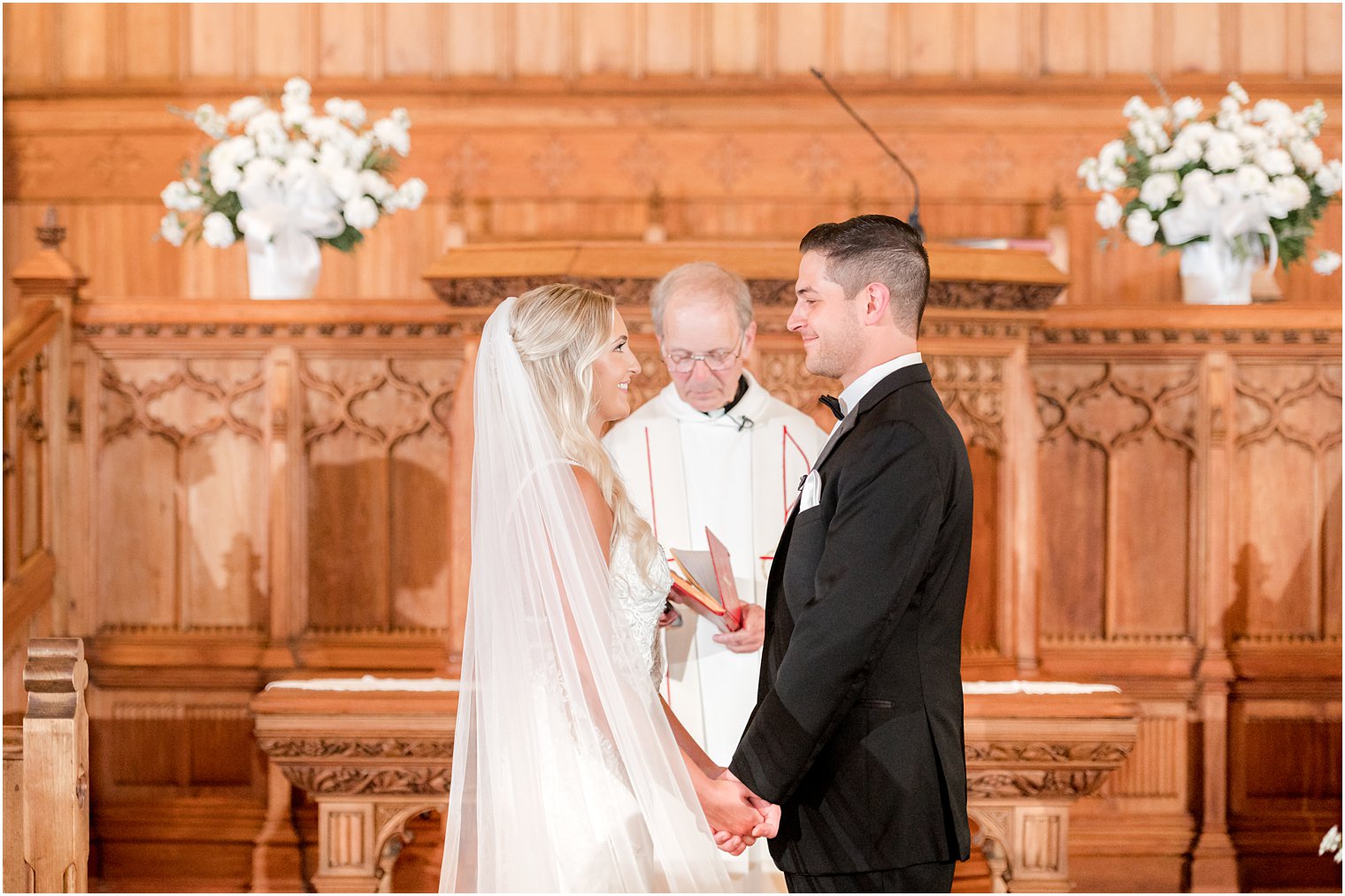 couple holds hands during vows for traditional church wedding in New Jersey