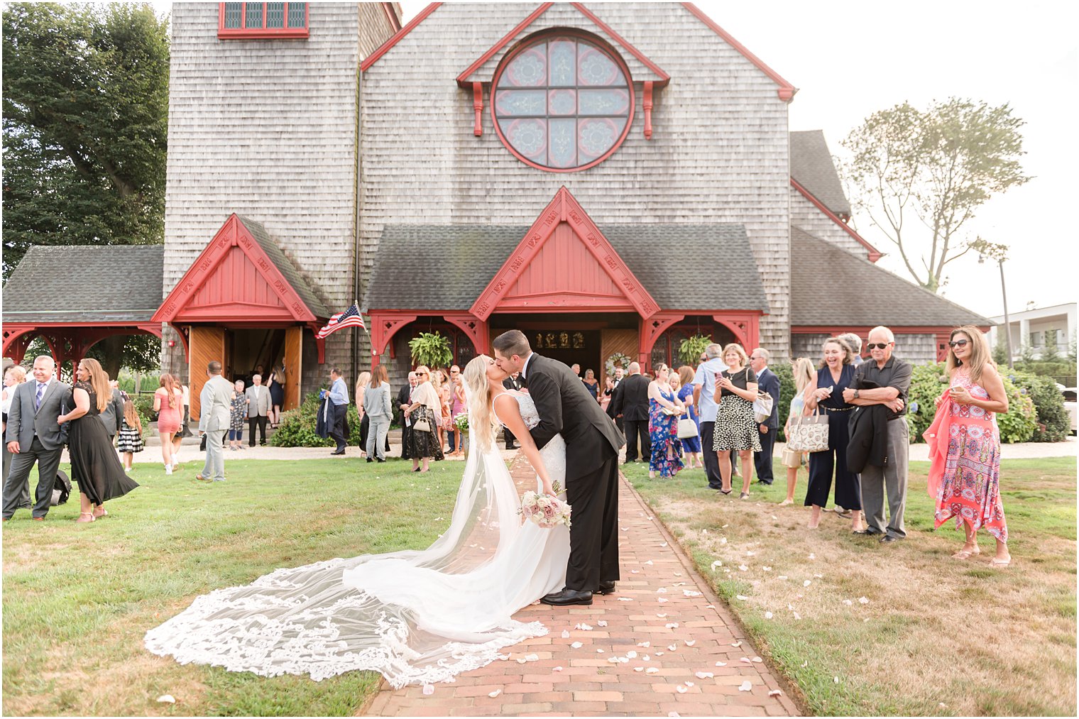 groom dips bride kissing her in front of guests at church in New Jersey