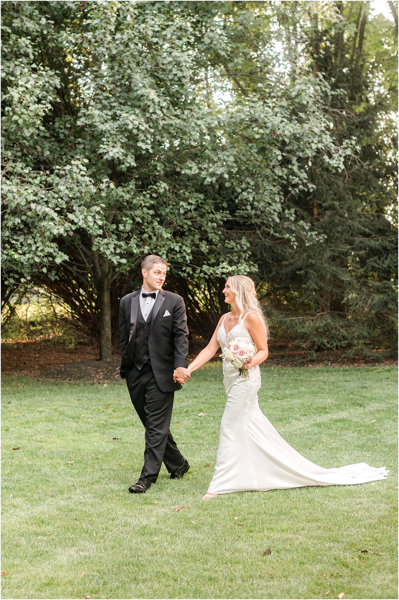 newlyweds hold hands walking through lawn at The English Manor