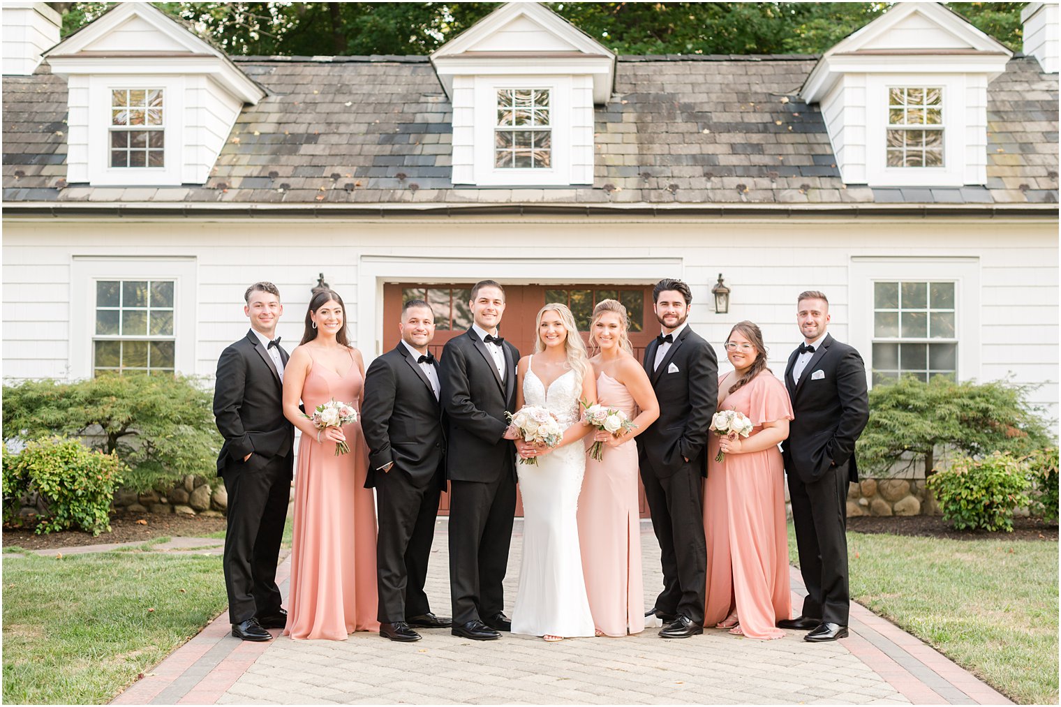 bride and groom stand with wedding party in coral and pink