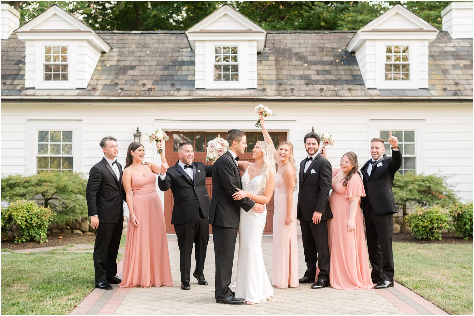 wedding party cheers at The English Manor while bride and groom kiss