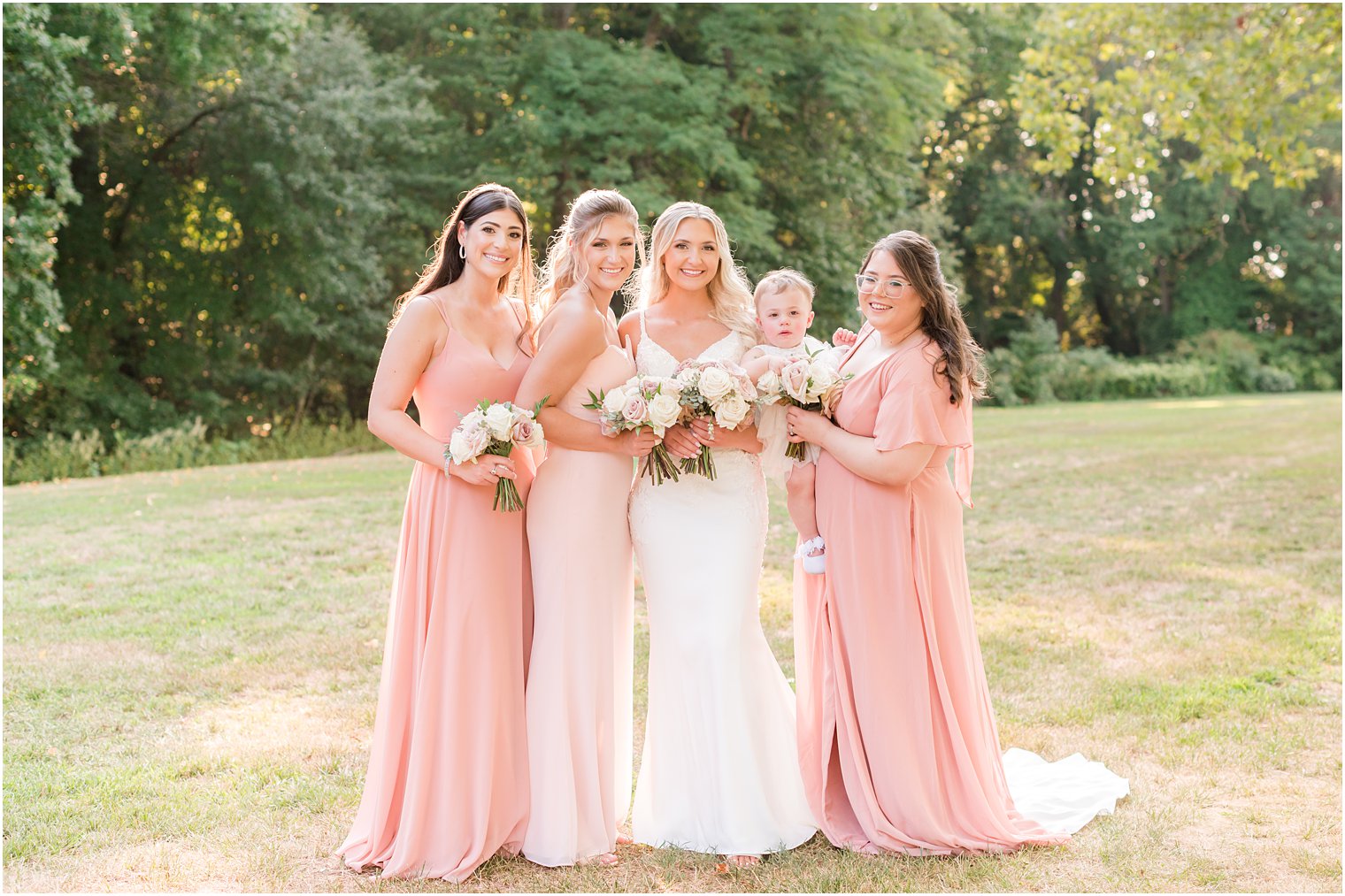 bride stands with bridesmaids in pink gowns