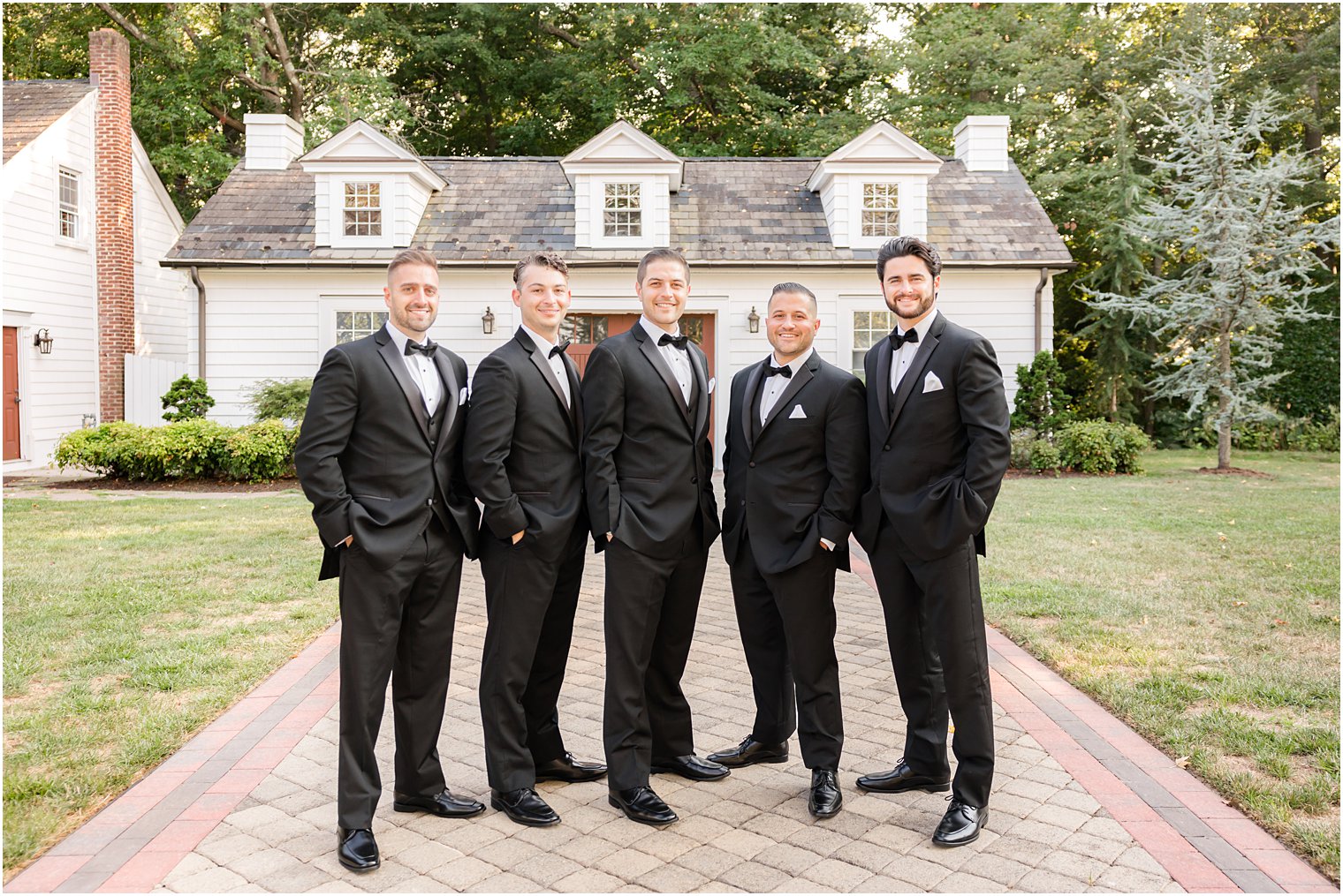 groom and groomsmen stand together outside The English Manor in classic suits