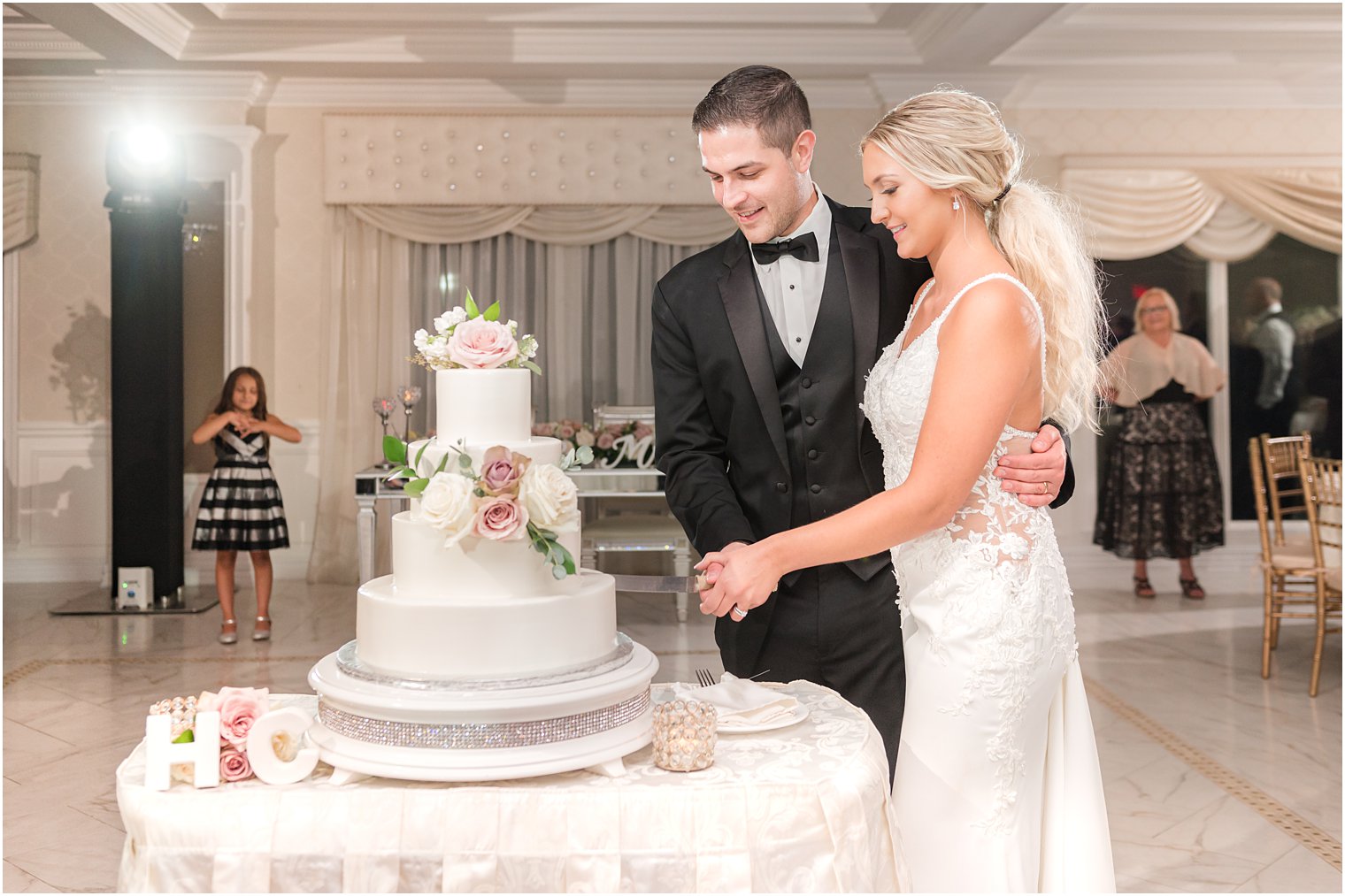 groom holds bride to him while cutting wedding cake