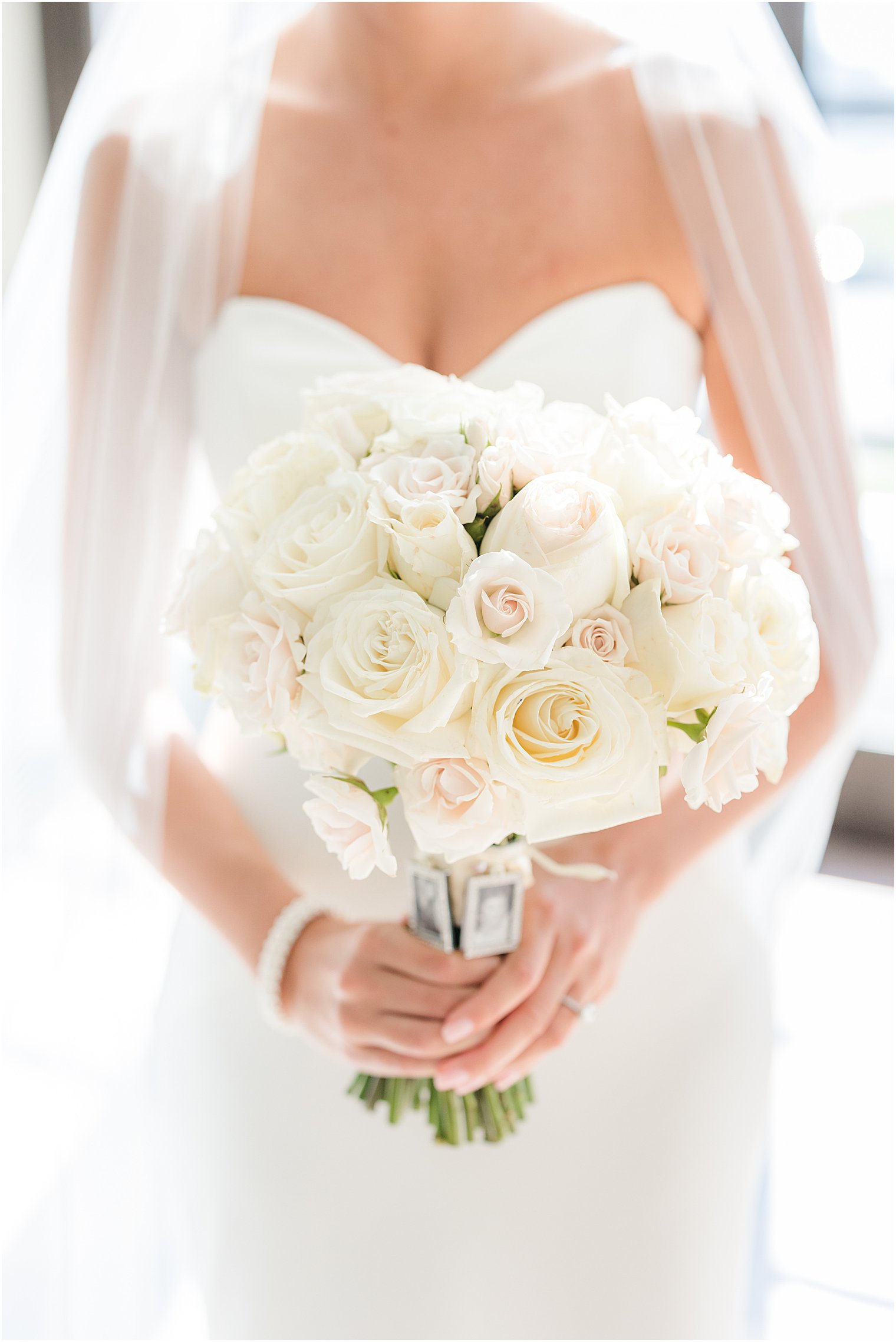 bride stands holding bouquet of ivory roses before NJ wedding 