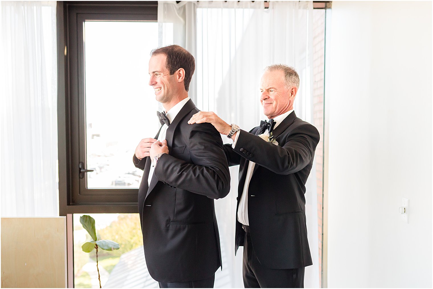 father helps groom into tux jacket before NJ wedding