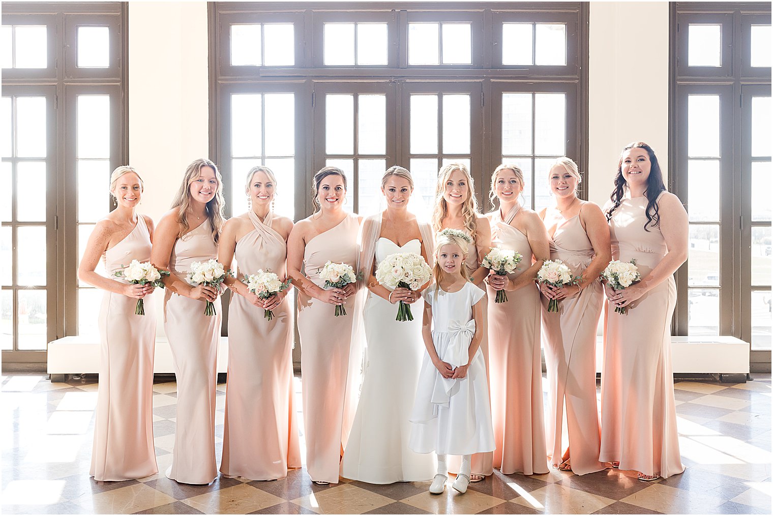 bridesmaids stand inside lobby of the Berkeley Oceanfront Hotel in pink gowns with ivory rose bouquets 