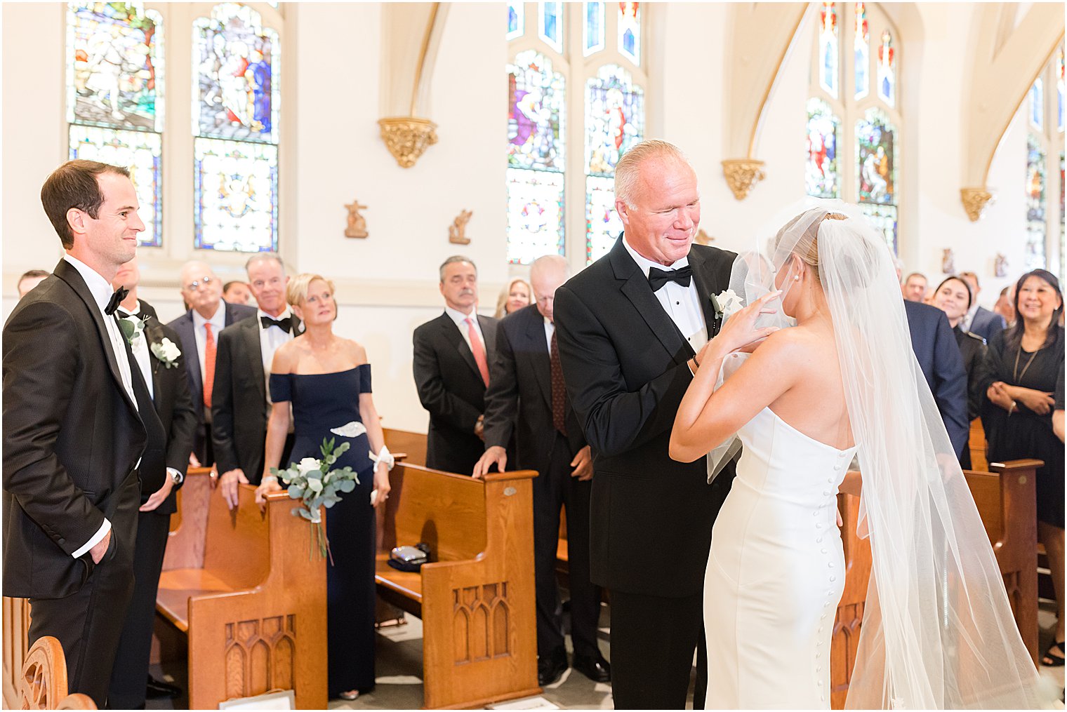 dad hugs daughter and moves veil during traditional church wedding at St. Mary's Catholic Church