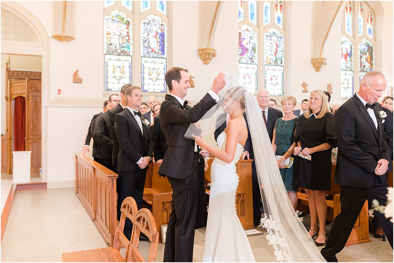 groom helps bride lift veil during traditional church wedding at St. Mary's Catholic Church