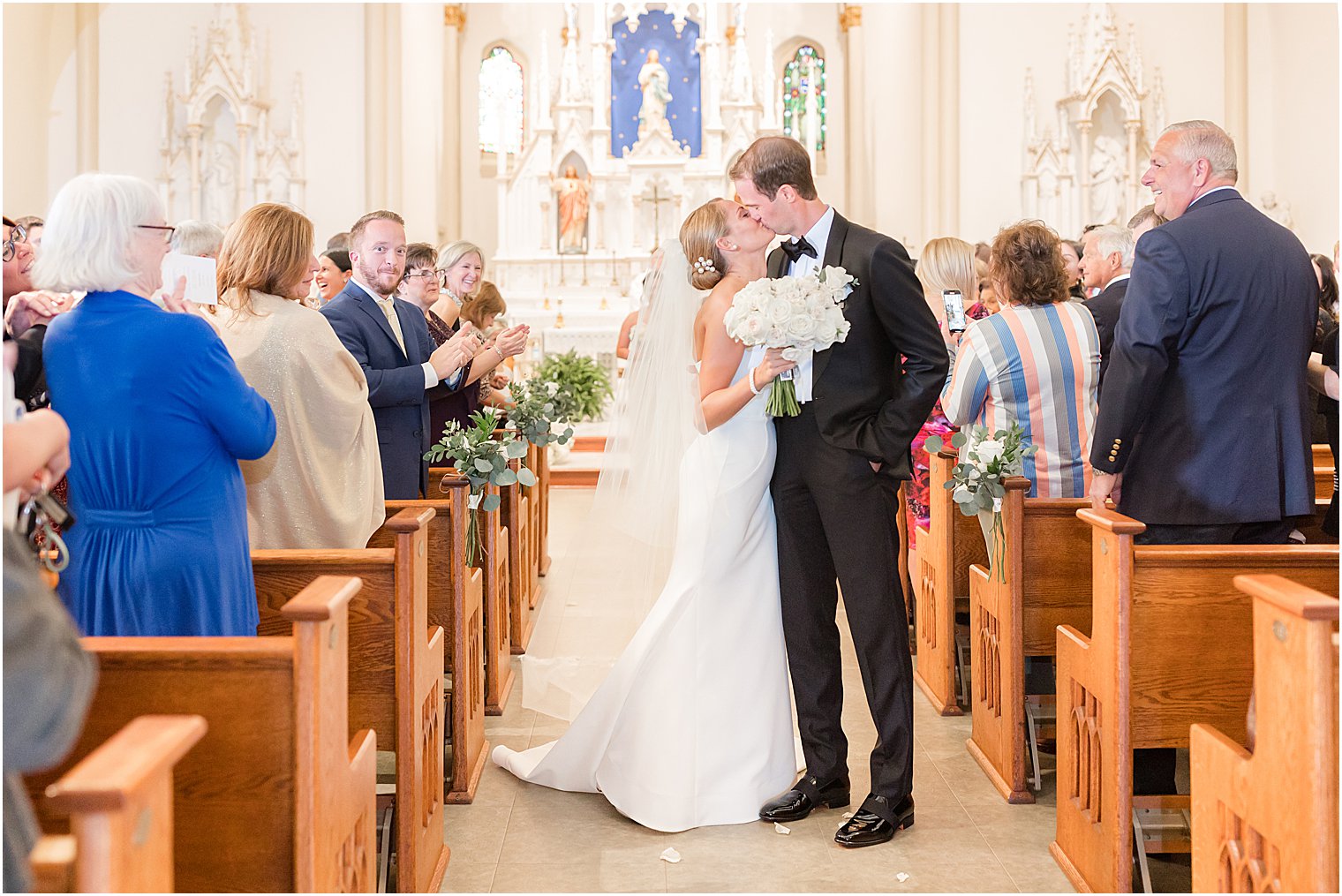newlyweds kiss in aisle after traditional church wedding at St. Mary's Catholic Church