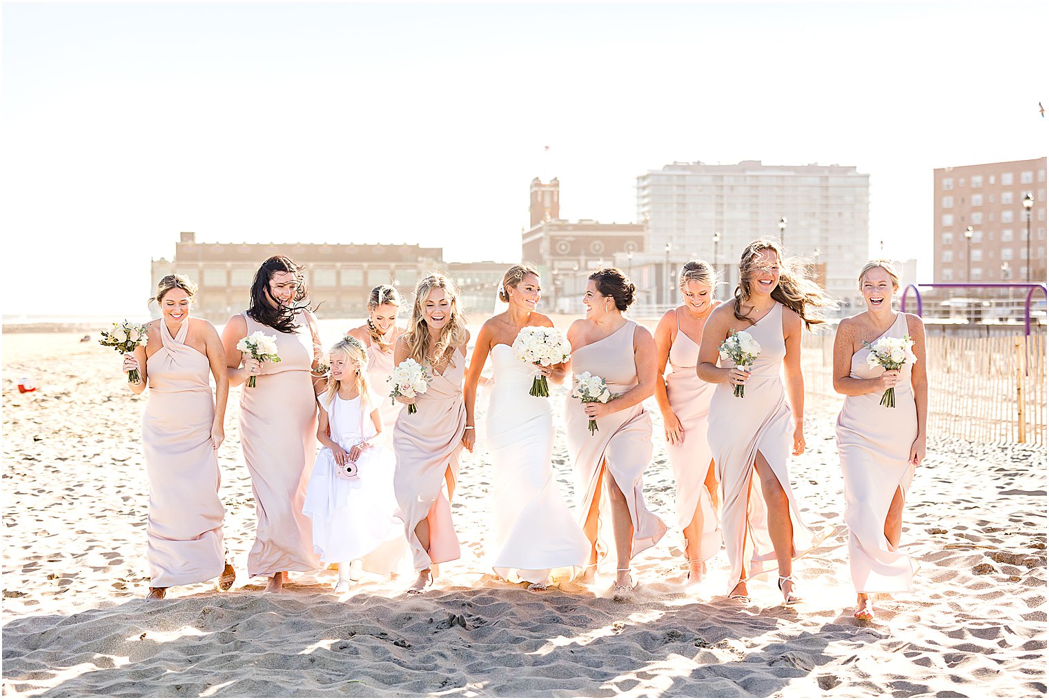 bride looks at bridesmaids in pink gowns at Asbury Park beach