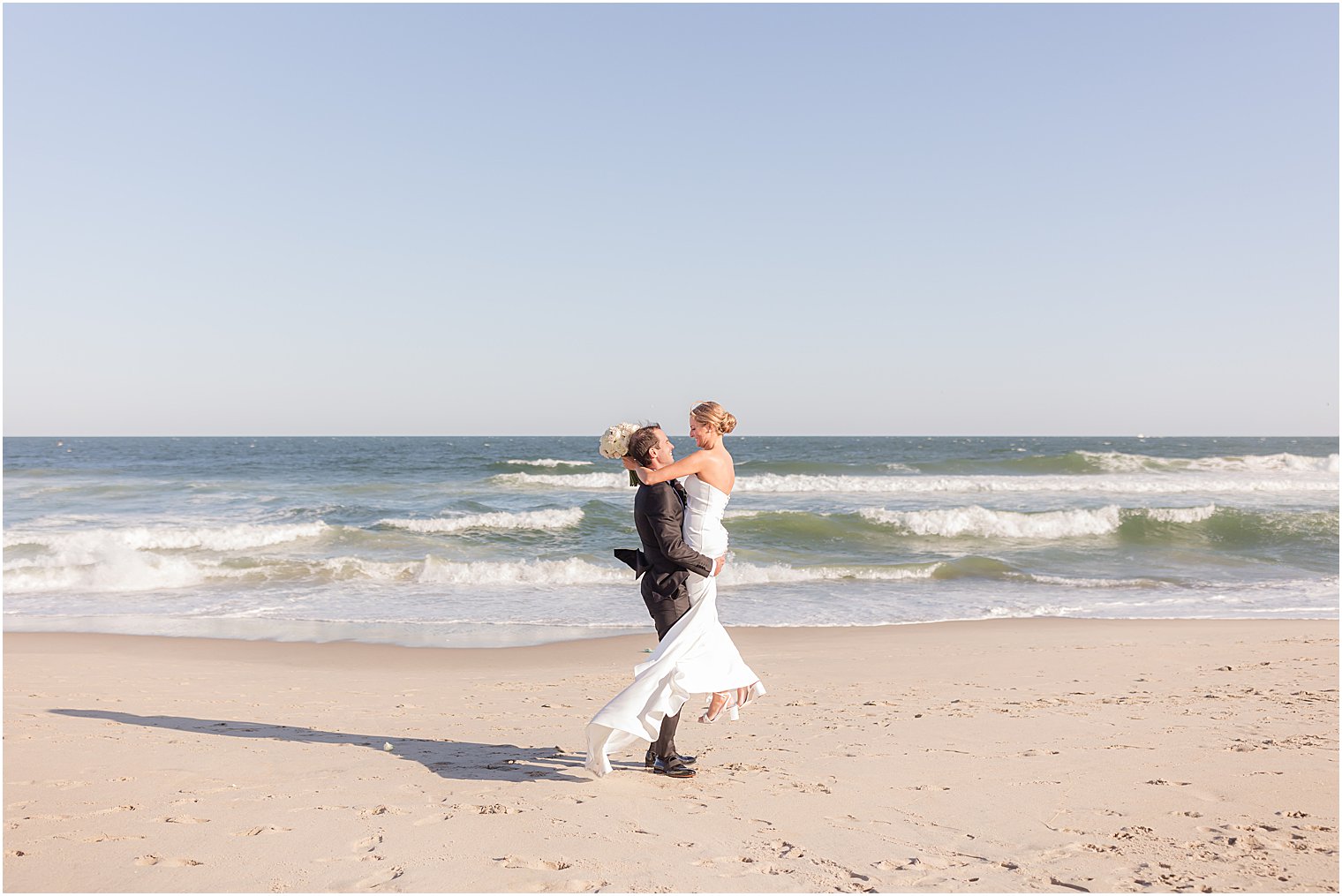 groom lifts bride in classic strapless gown at Asbury Park