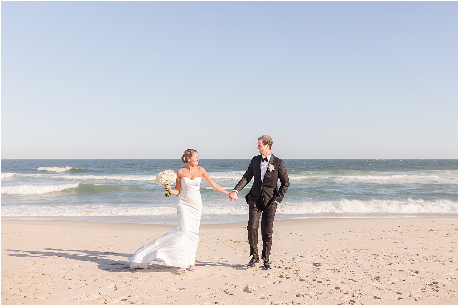 bride and groom walk on beach at Asbury Park