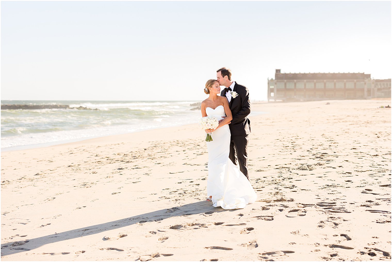 groom hugs bride from behind kissing her temple 