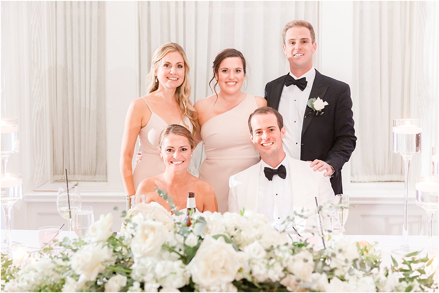 newlyweds sit with siblings behind them at sweetheart table 