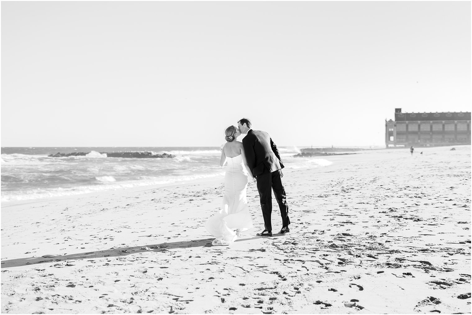 newlyweds lean for kiss on beach at Asbury Park