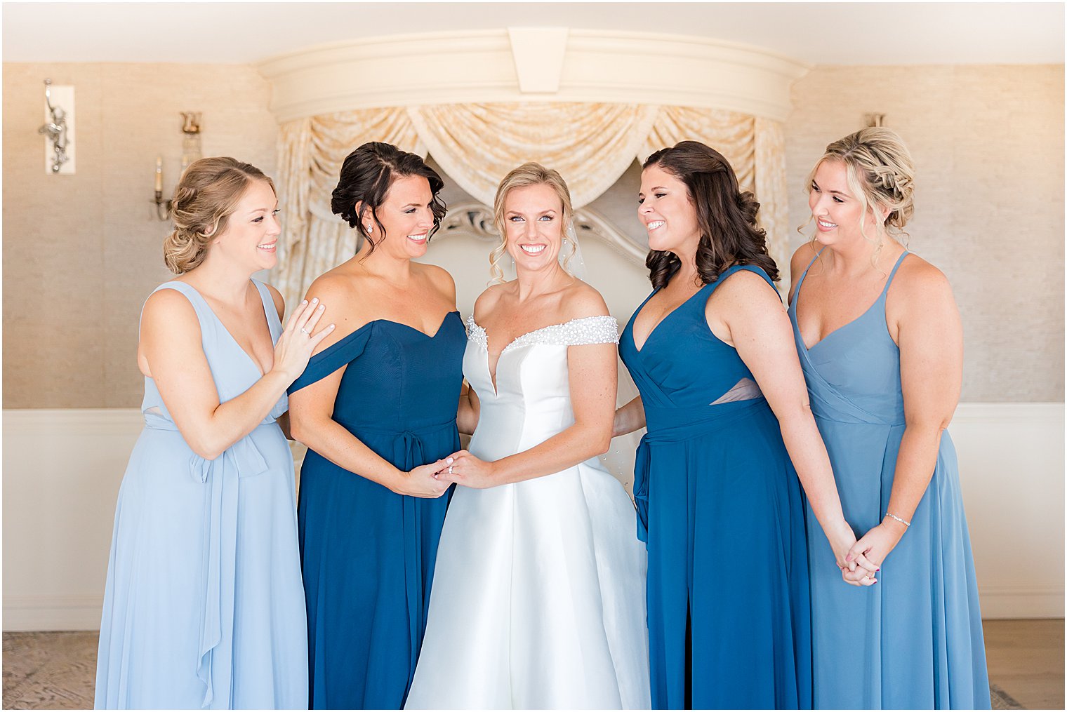 bride stands with bridesmaids in various blue gowns