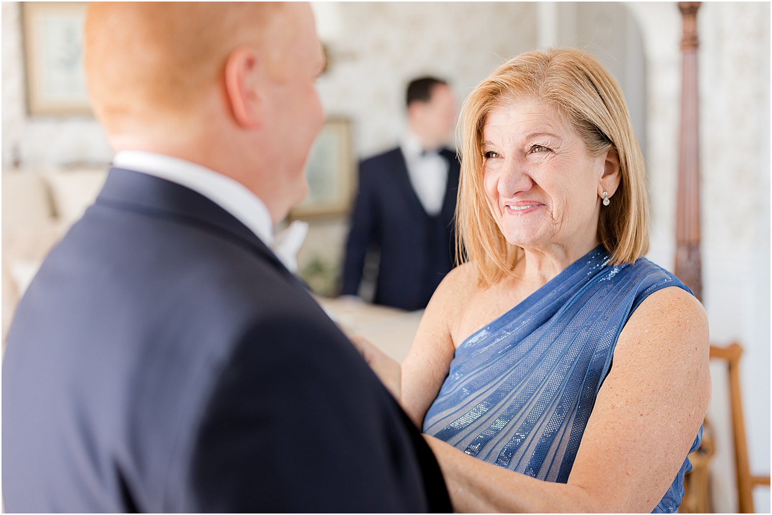 mother in blue gown pins boutonnière on groom