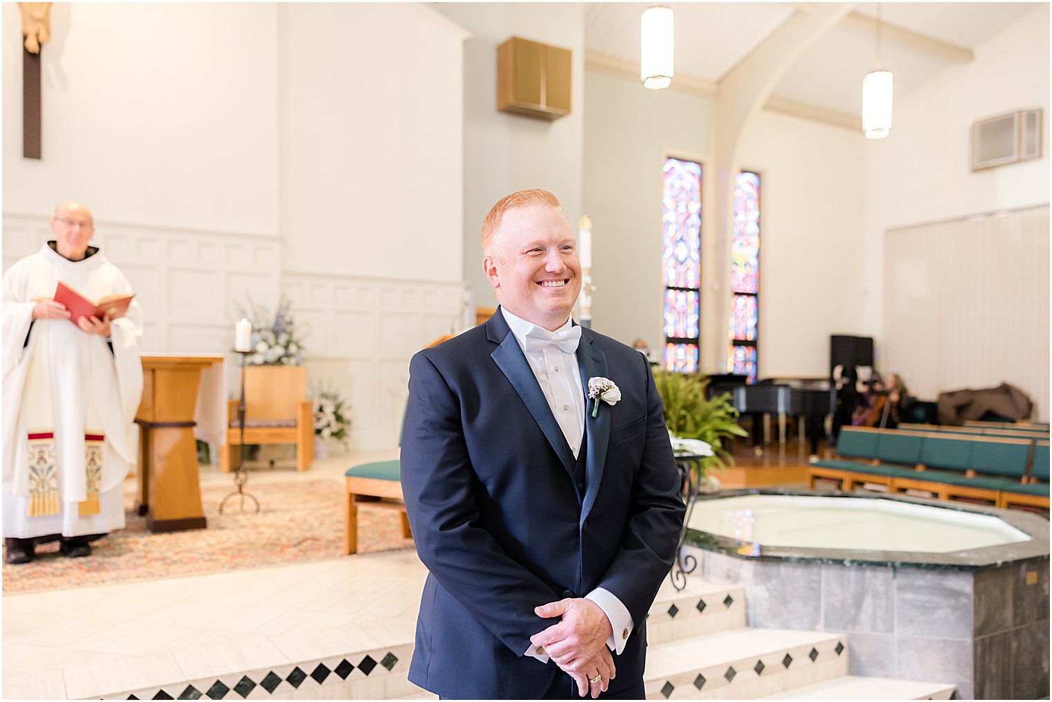 groom smiles watching bride walk down aisle for traditional church wedding on Long Beach Island