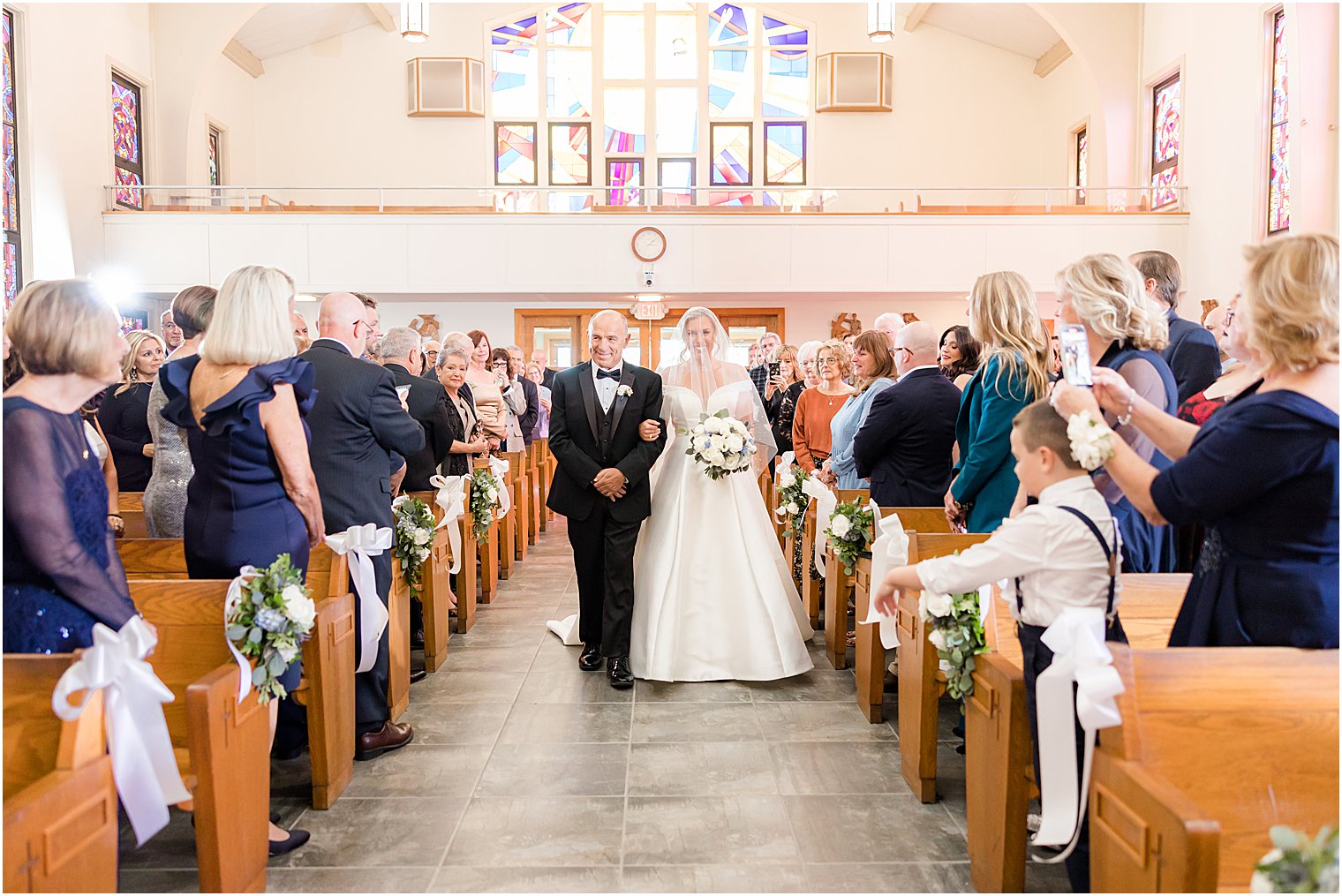 bride walks down aisle smiling at groom during traditional church wedding on Long Beach Island