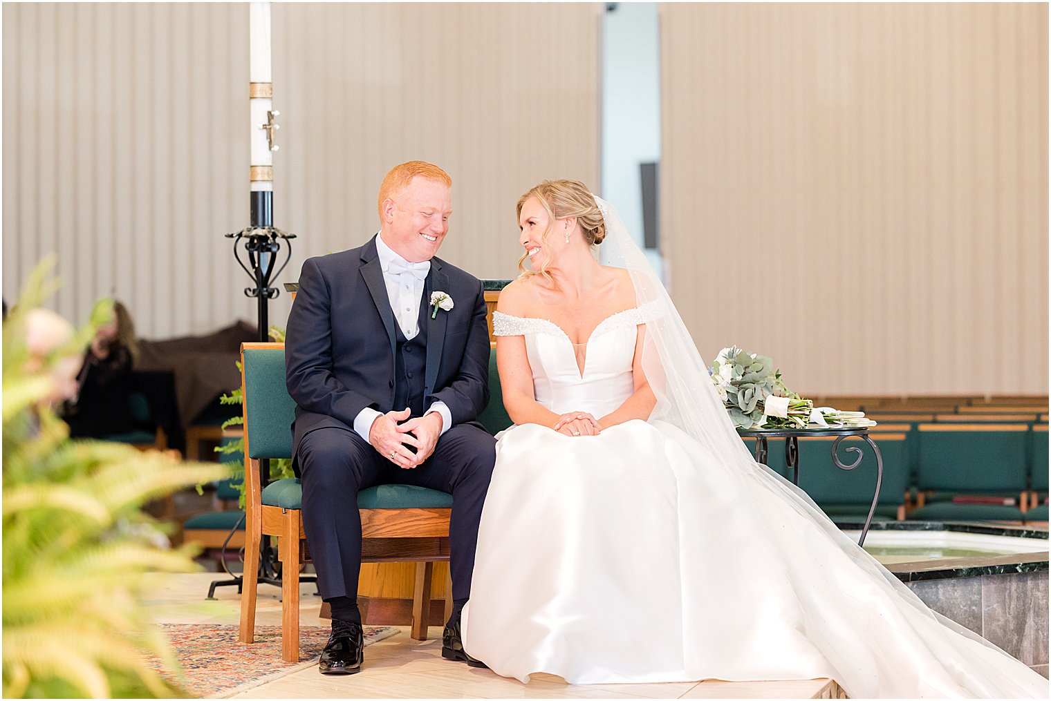 bride and groom smile sitting together during traditional church wedding on Long Beach Island
