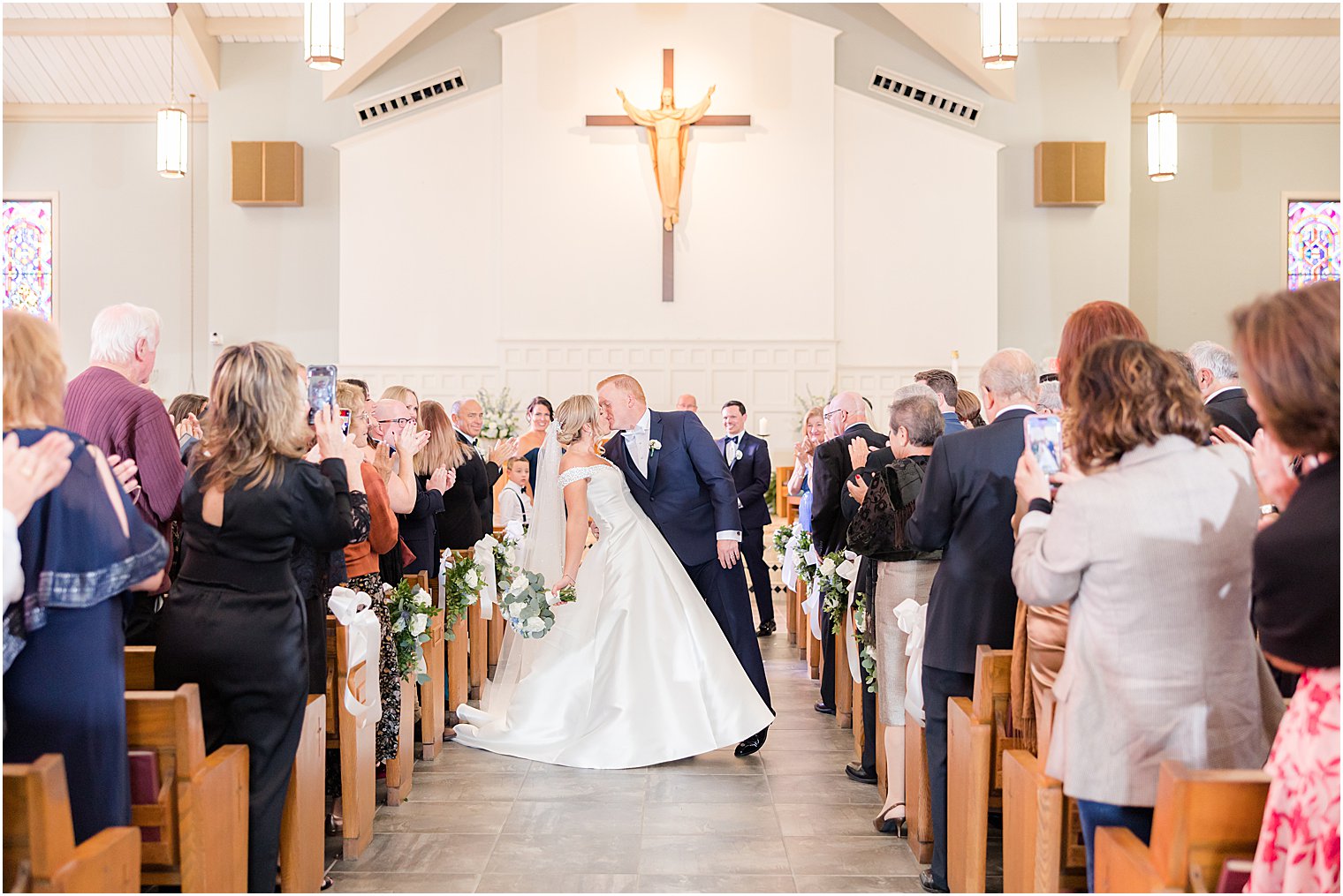 groom dips bride kissing her in aisle after traditional church wedding on Long Beach Island