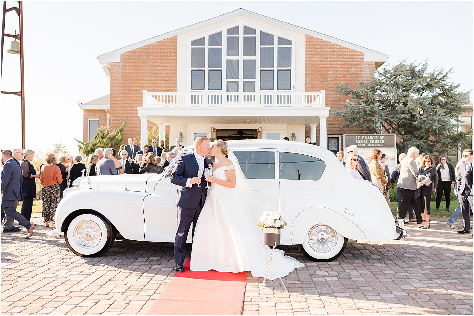 bride and groom kiss outside white classic car