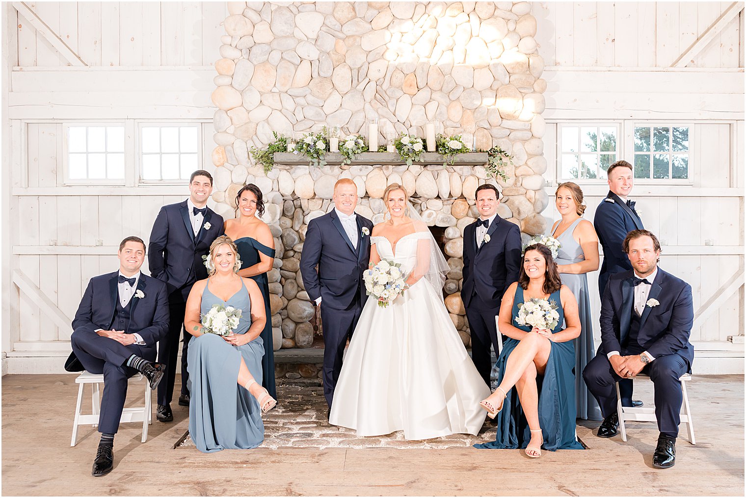 bride and groom pose with wedding party by stone fireplace at Bonnet Island Estate