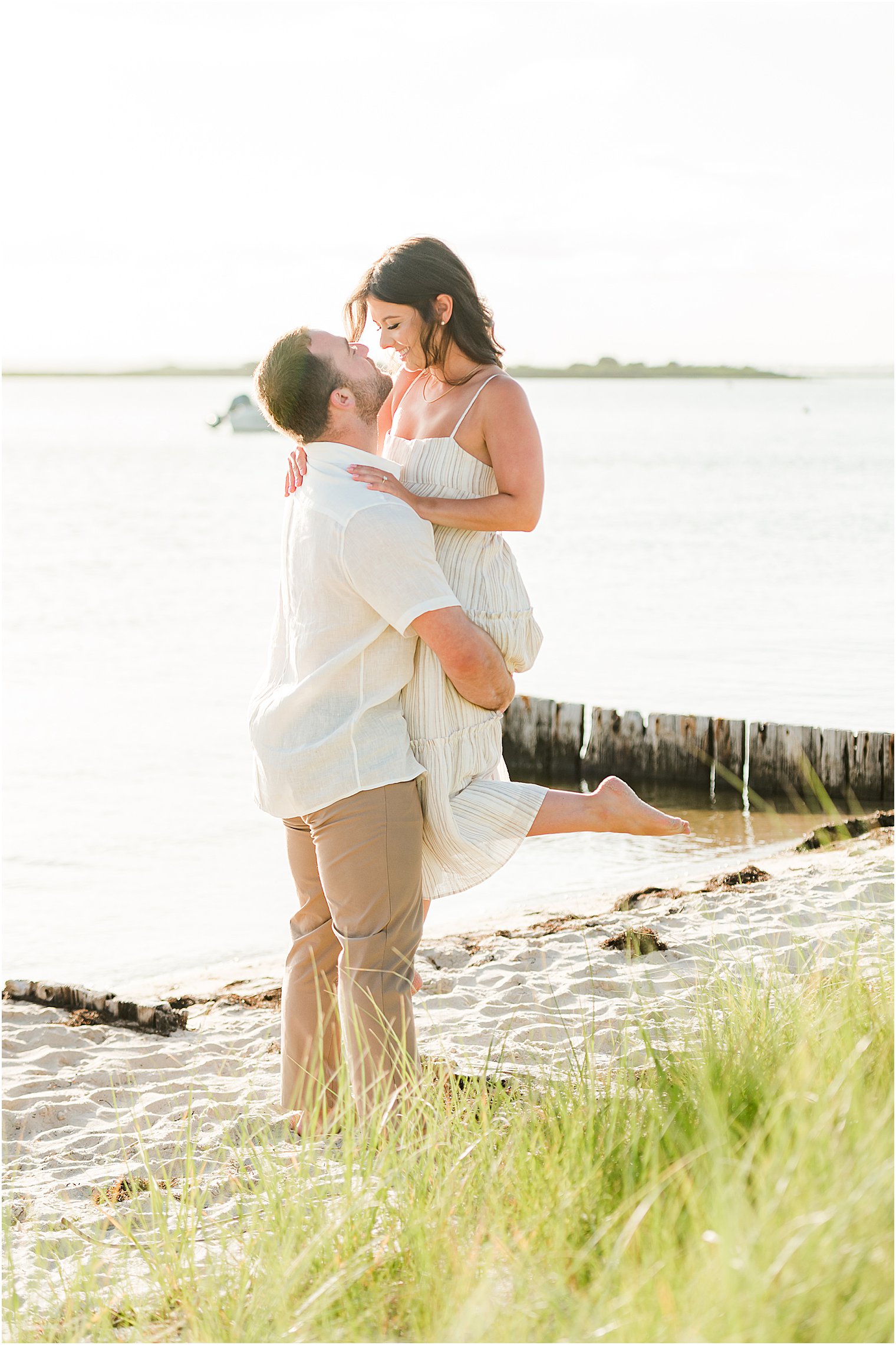 groom lifts bride up on beach during engagement session